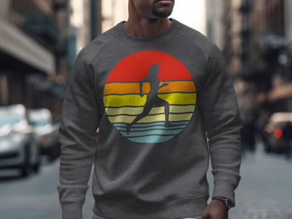 Gray crewneck sweatshirt with runner silhouette against a colorful sunset circle.