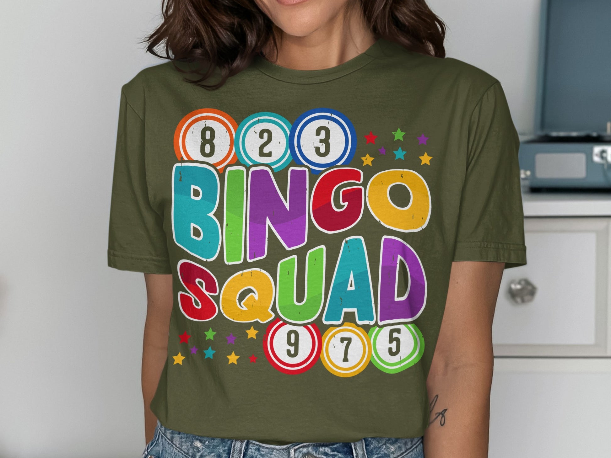 Olive green t-shirt with "BINGO SQUAD" in colorful letters and bingo balls.