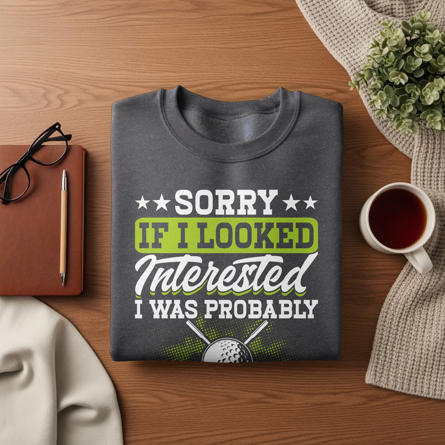 Dark grey sweatshirt with text "Sorry if I looked interested, I was probably..." and a golf ball.