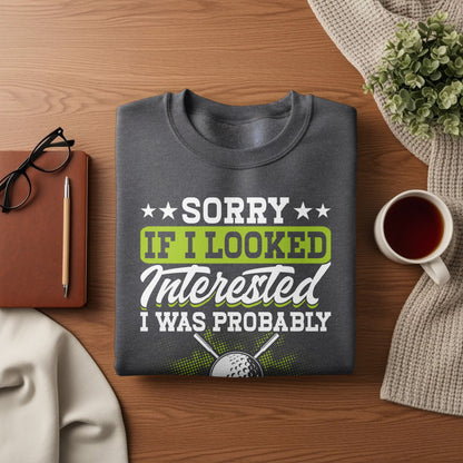 Dark grey sweatshirt with text "Sorry if I looked interested, I was probably..." and a golf ball.