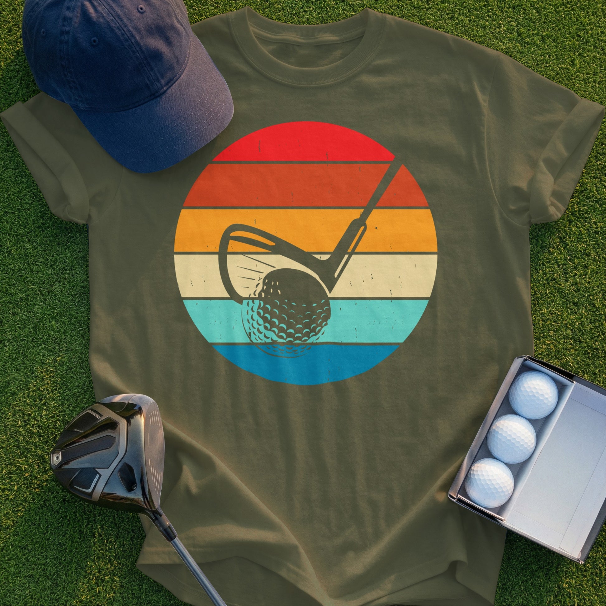 Golf club hitting a ball inside a retro sunset circle graphic on a shirt.