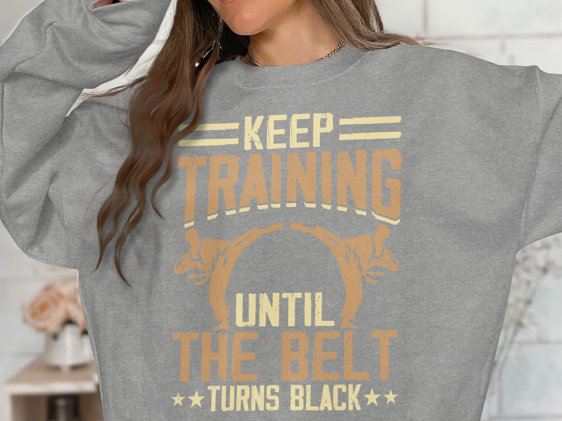 Grey sweatshirt with "Keep Training Until The Belt Turns Black" text and martial artists.