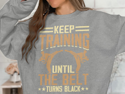 Grey sweatshirt with "Keep Training Until The Belt Turns Black" text and martial artists.