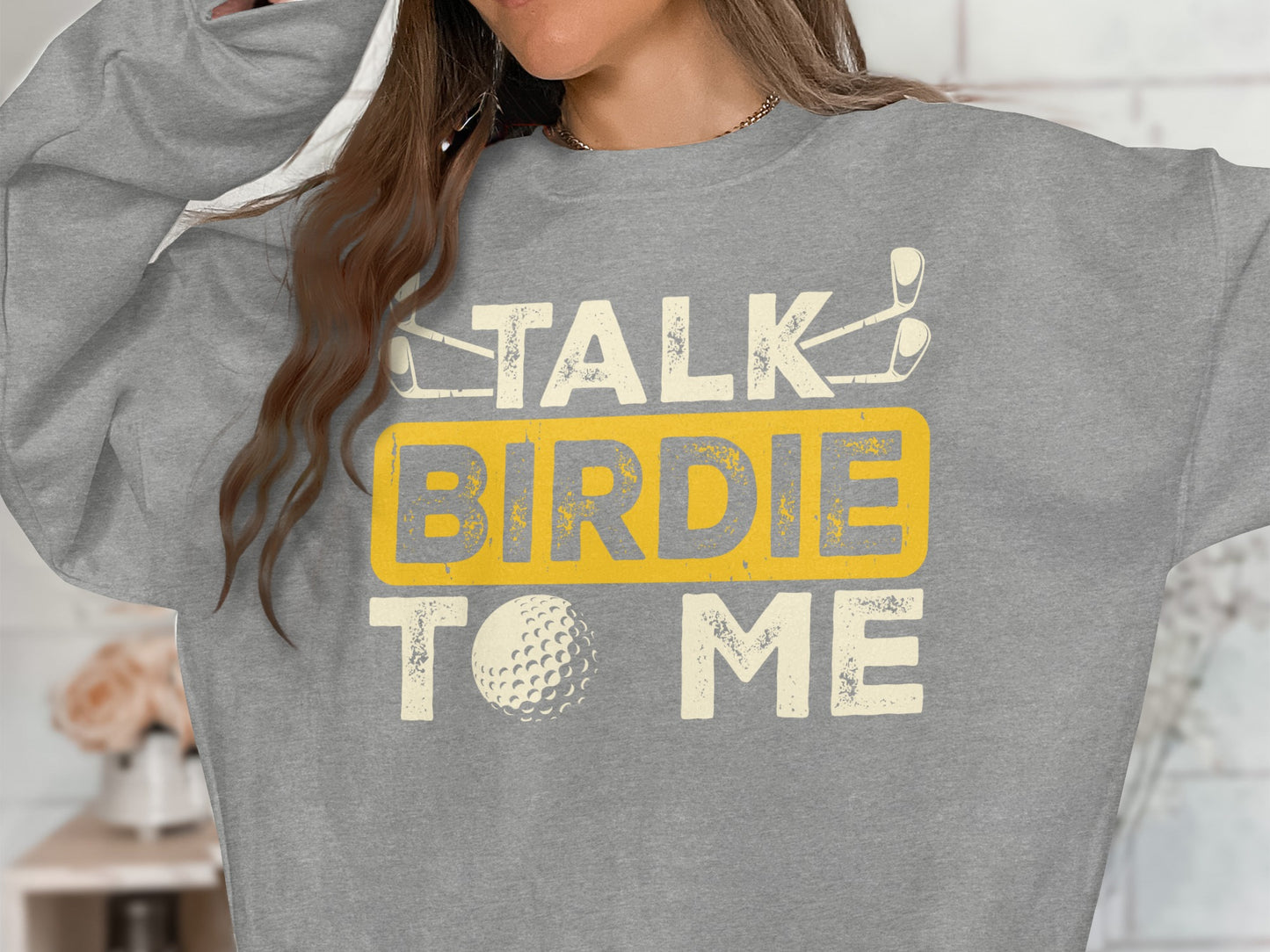 Grey sweatshirt with "Talk Birdie To Me" text and golf graphics.