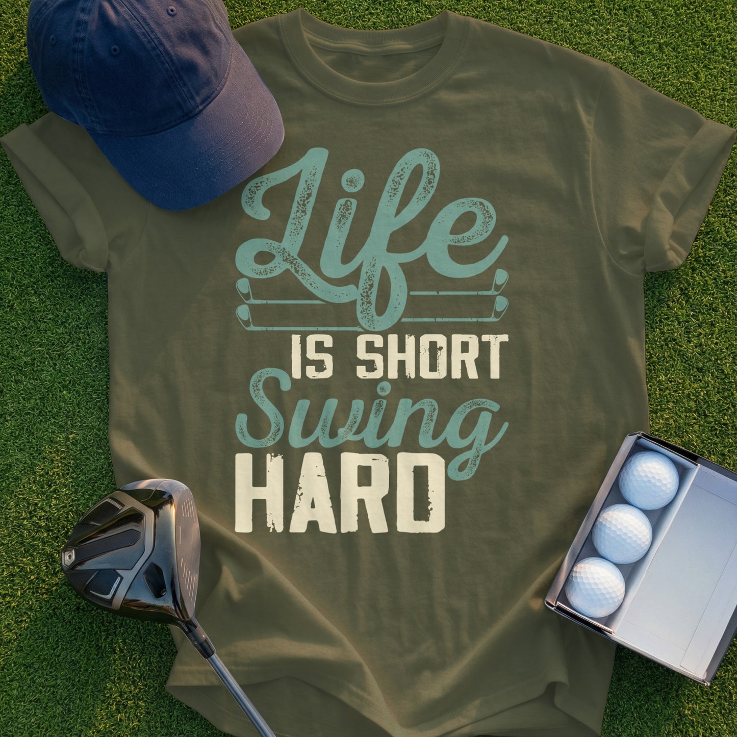 Olive green t-shirt with "Life Is Short Swing HARD" text and golf accessories.