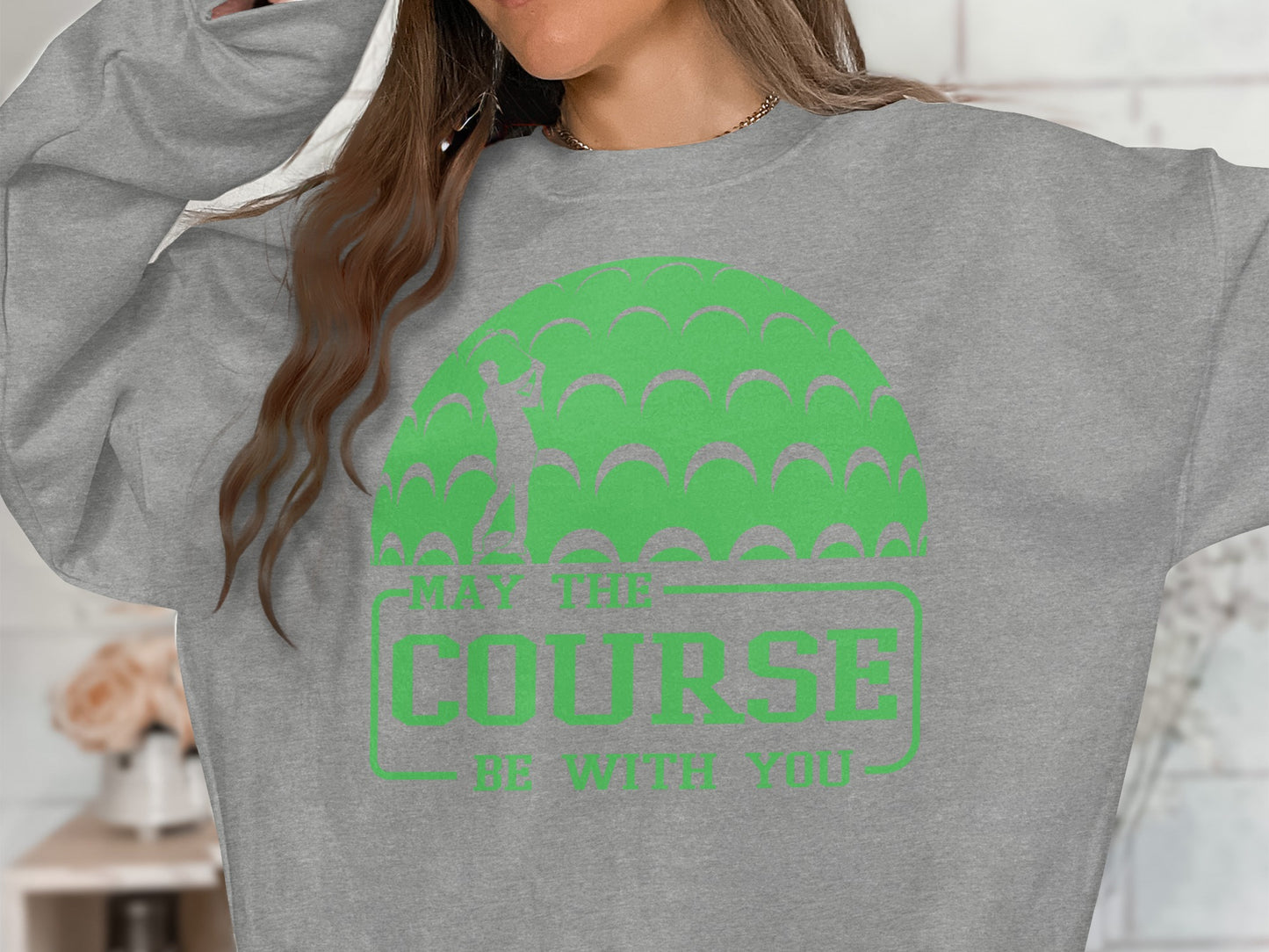 Grey sweatshirt with "May the course be with you" text and golf ball pattern.