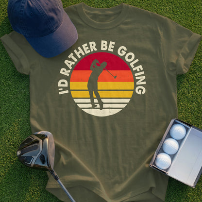 Olive green t-shirt with "I'd Rather Be Golfing" text and a sunset golfer graphic.