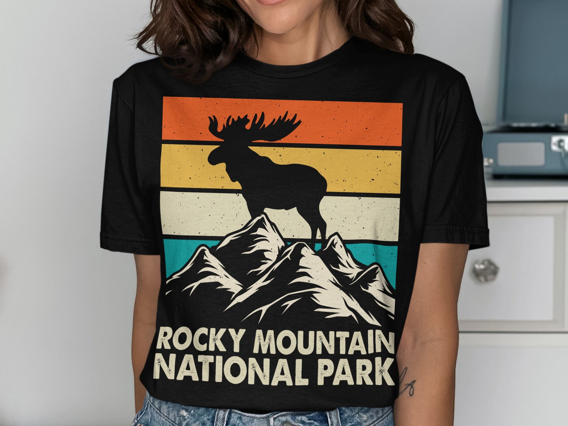 Silhouette of a moose on a mountain peak with "Rocky Mountain National Park" text.