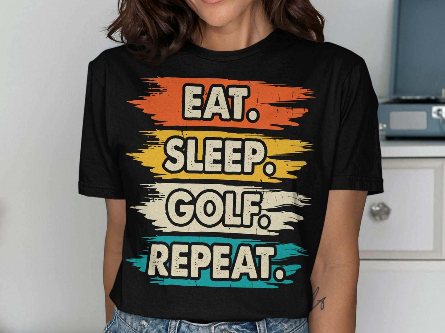 Black t-shirt with "Eat. Sleep. Golf. Repeat." text in distressed colorful stripes.