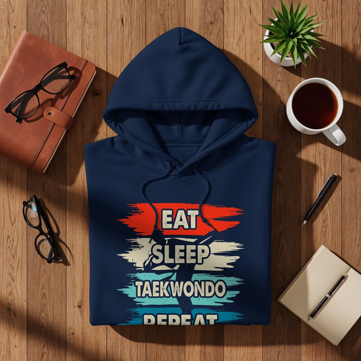Navy blue hoodie with "Eat Sleep Taekwondo Repeat" graphic on a wooden background.