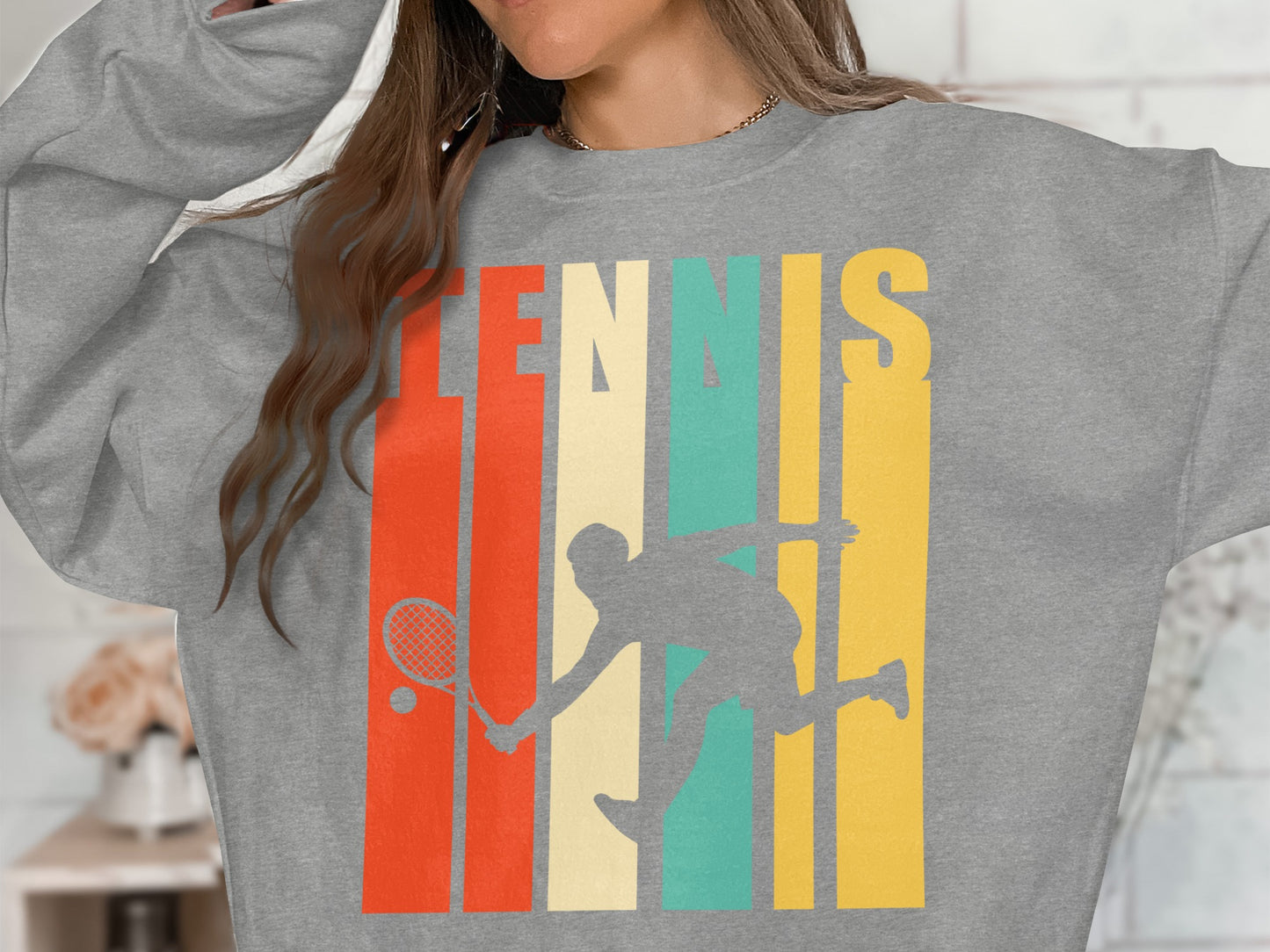 Grey sweatshirt with retro tennis player graphic and colorful stripes.