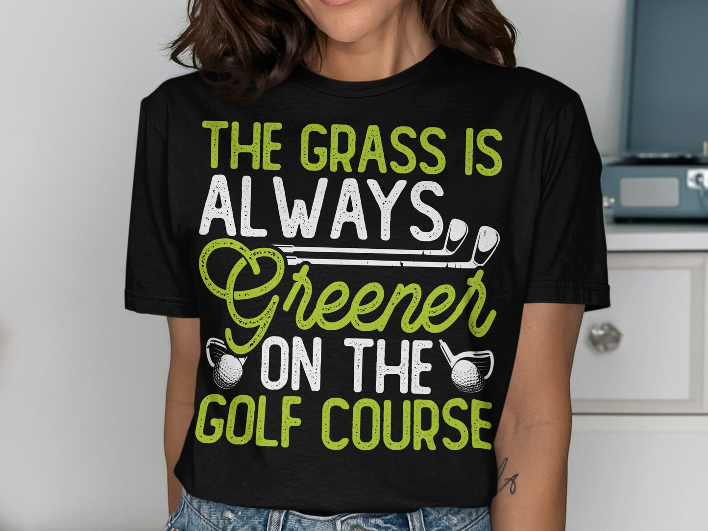 Black t-shirt with text "The Grass is Always Greener on the Golf Course".