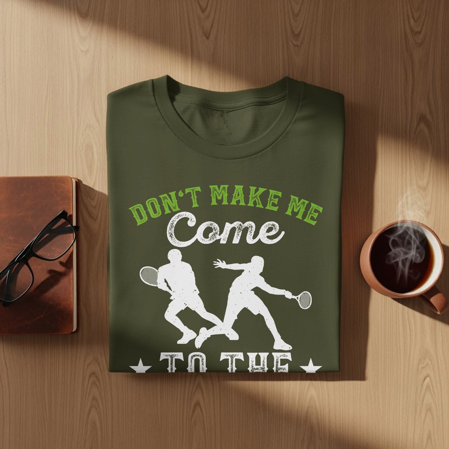 Green t-shirt with white graphic of two tennis players and text "Don't Make Me Come To The".