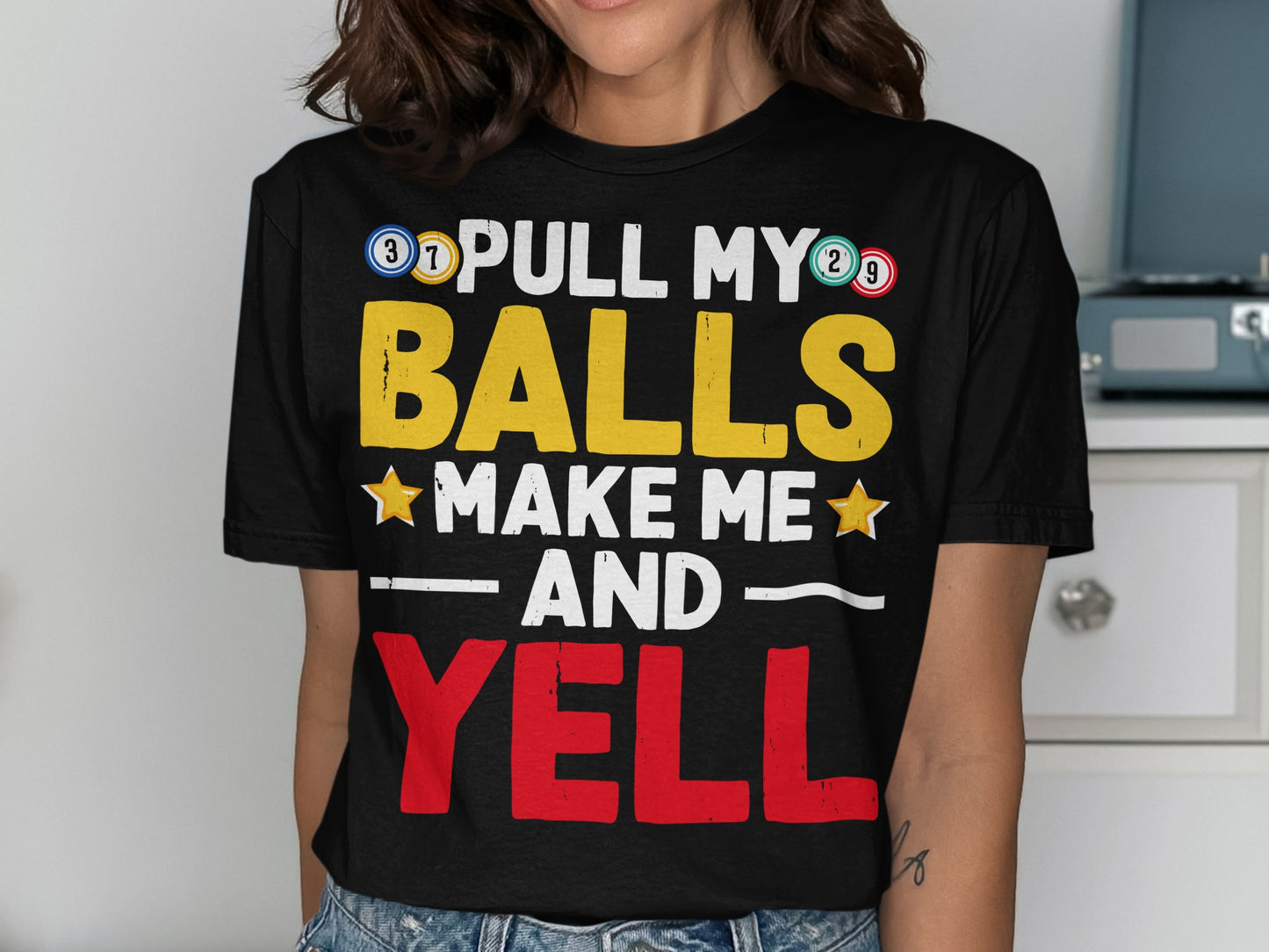 Black t-shirt with "PULL MY BALLS MAKE ME AND YELL" text in yellow and red.