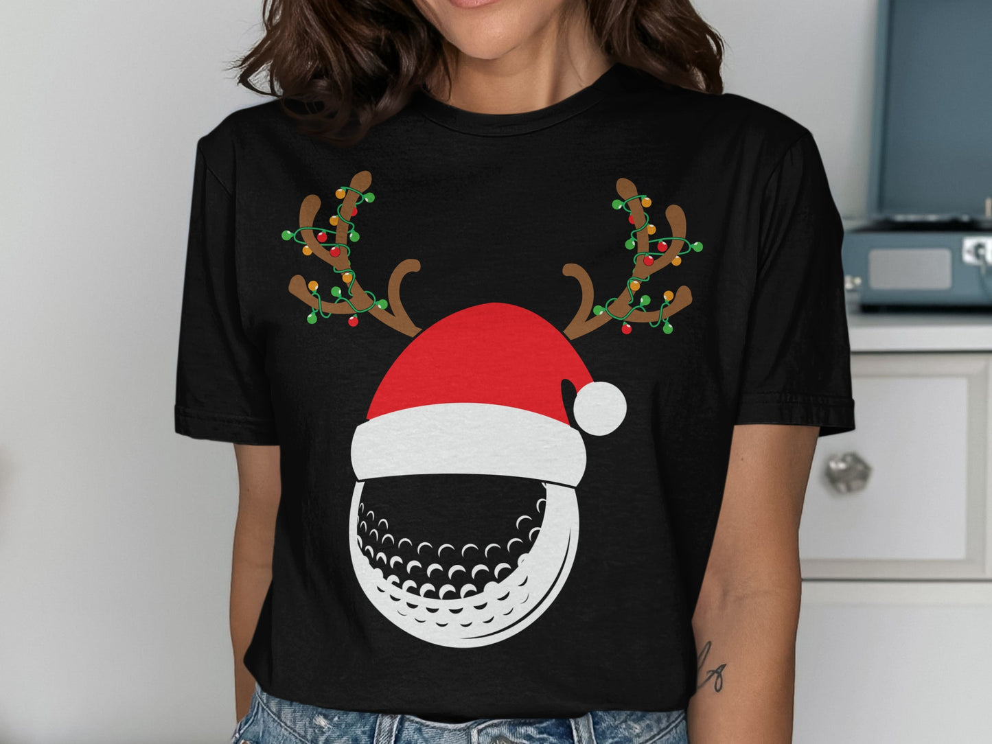 Black t-shirt with a graphic of a golf ball wearing a Santa hat and reindeer antlers.