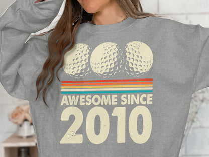 Grey sweatshirt with golf balls and "Awesome Since 2010" text.