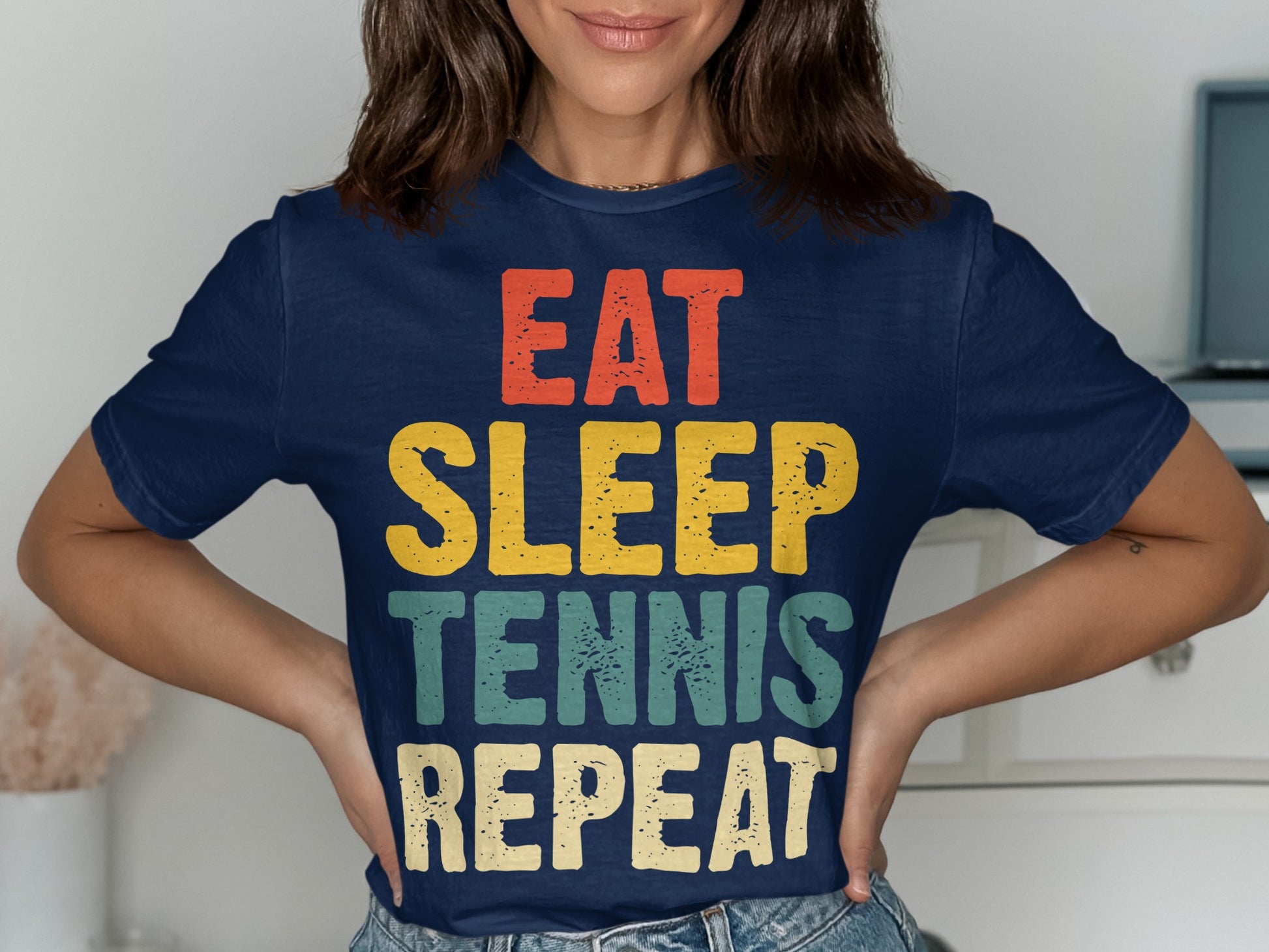 Navy t-shirt with "EAT SLEEP TENNIS REPEAT" text in colorful block letters.