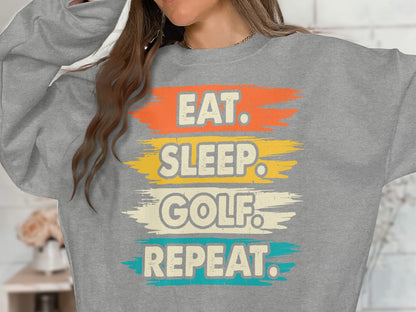 Grey sweatshirt with "Eat. Sleep. Golf. Repeat." text in colorful brush strokes.