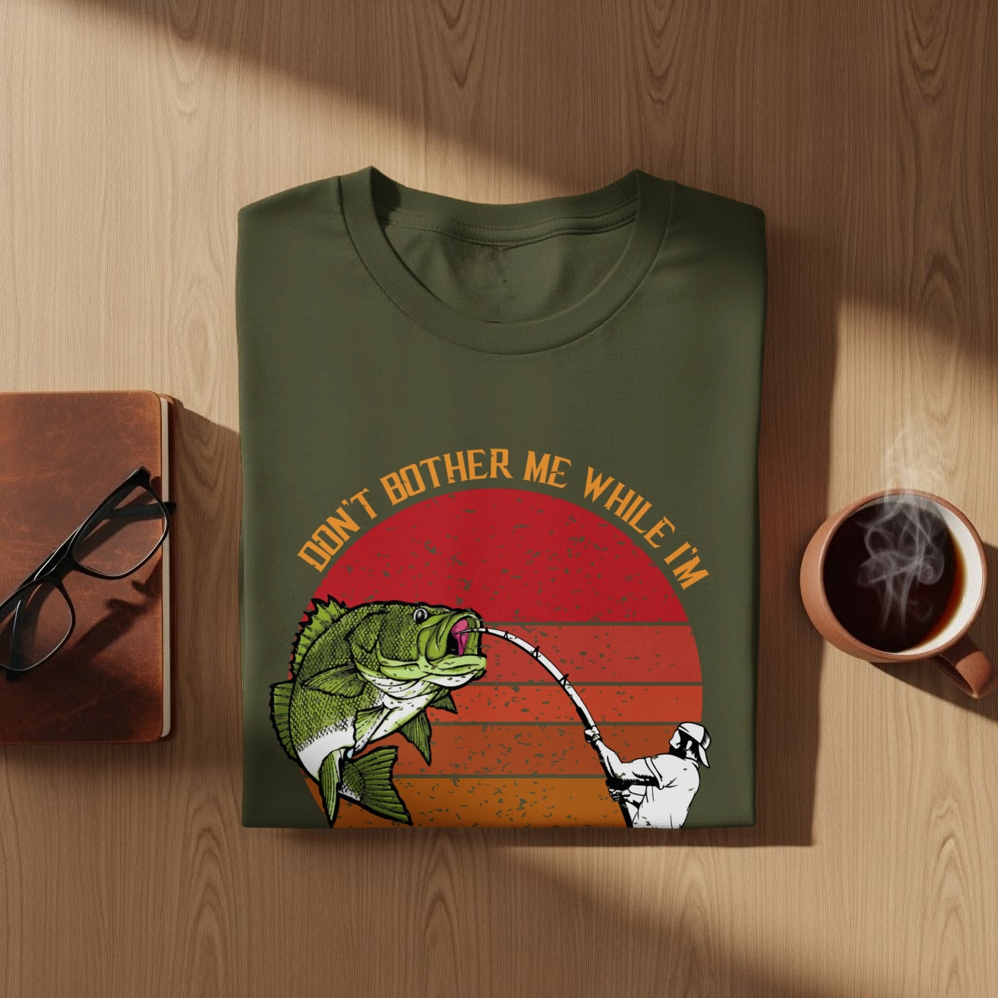 Green t-shirt with text "Don't bother me while I'm fishing" and a graphic of a fisherman catching a bass.