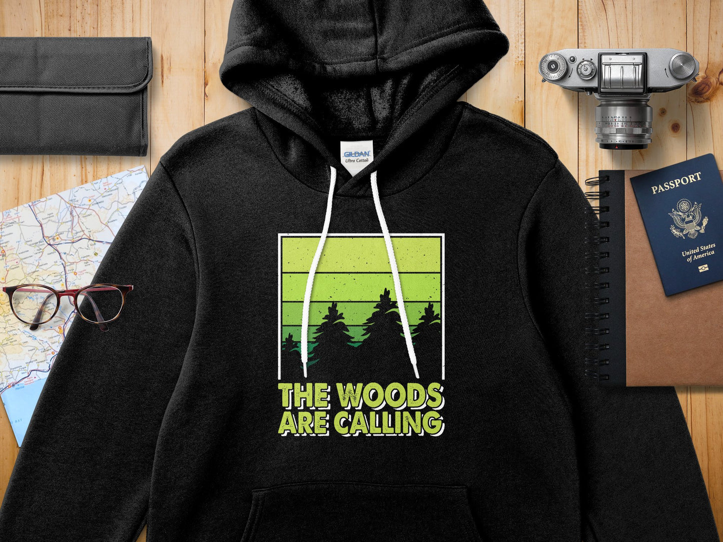 Black hoodie with "The Woods Are Calling" graphic featuring green trees.