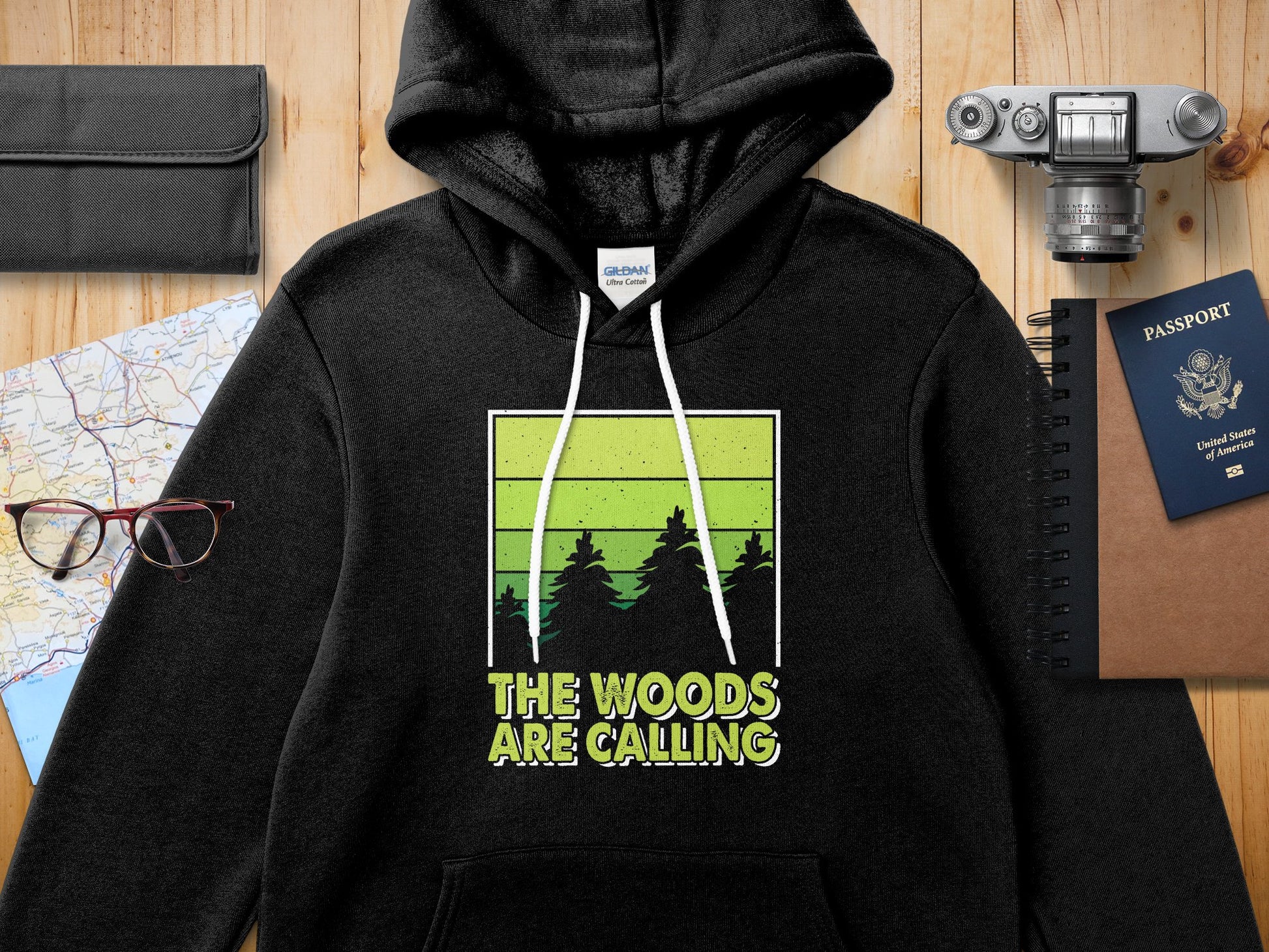 Black hoodie with "The Woods Are Calling" graphic featuring green trees.