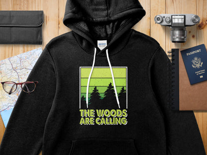 Black hoodie with "The Woods Are Calling" graphic featuring green trees.