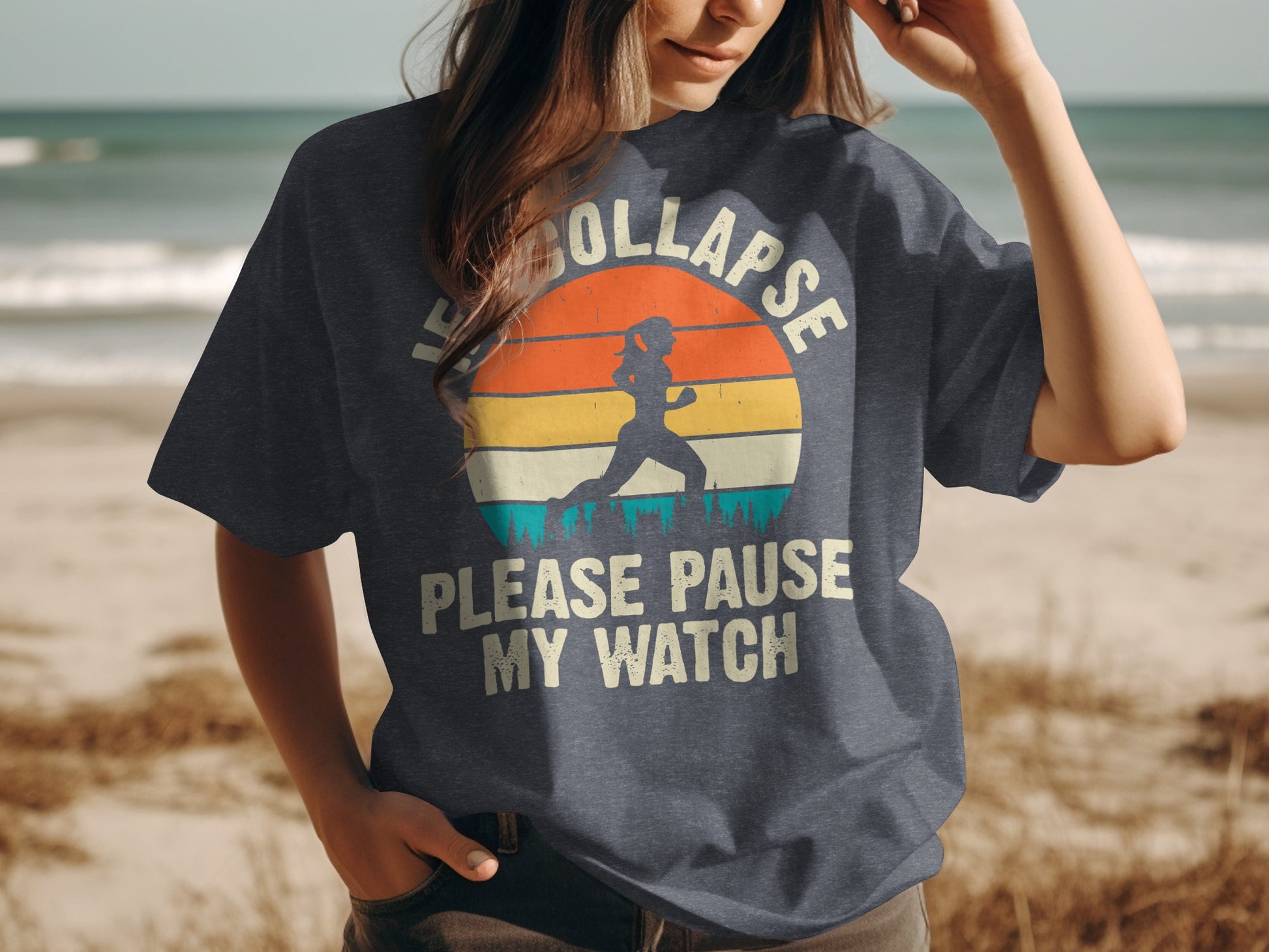 Woman wearing dark t-shirt with sunset graphic and text "Please Pause My Watch".