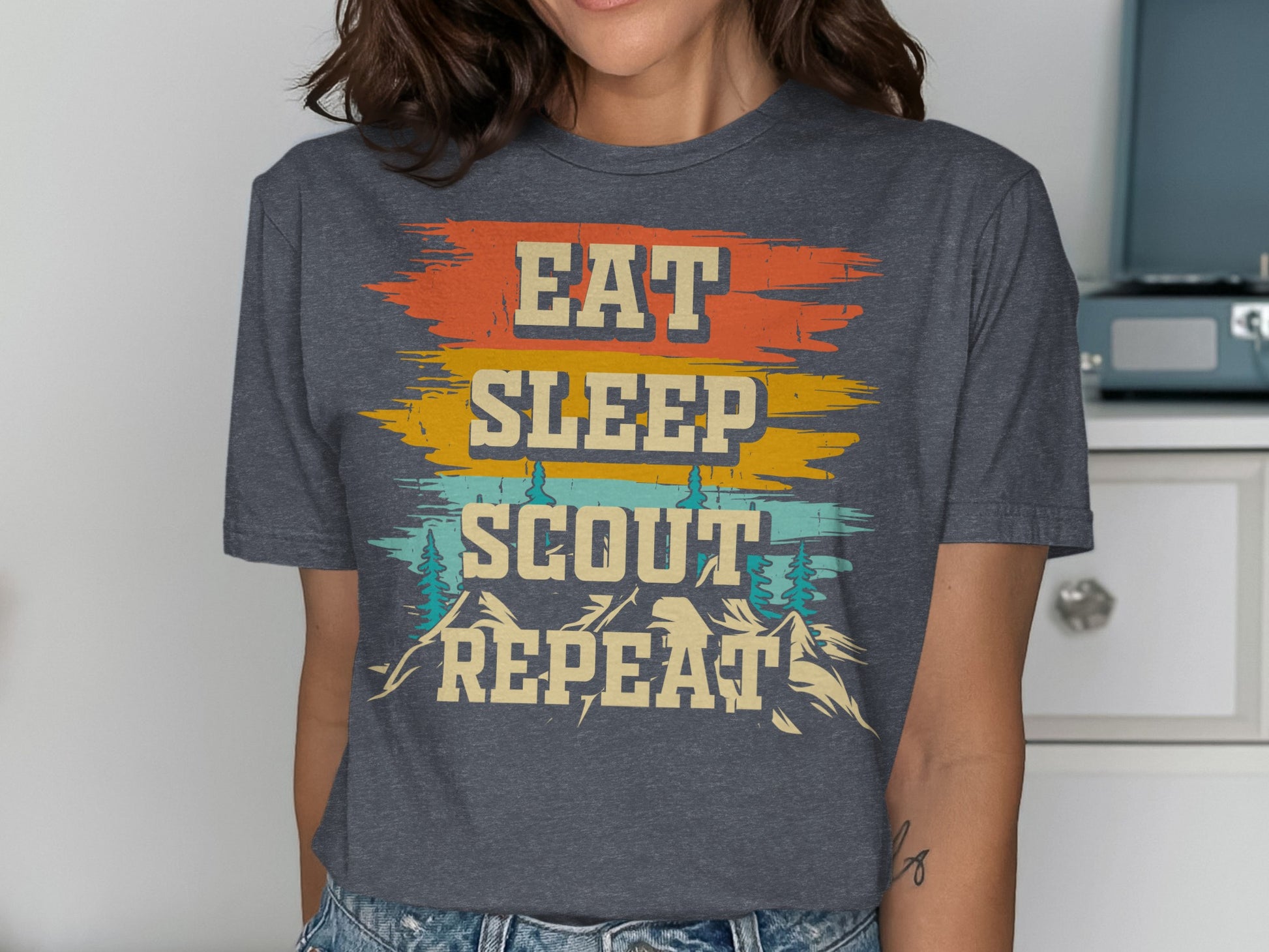 Dark grey t-shirt with "Eat Sleep Scout Repeat" text and mountain graphics.