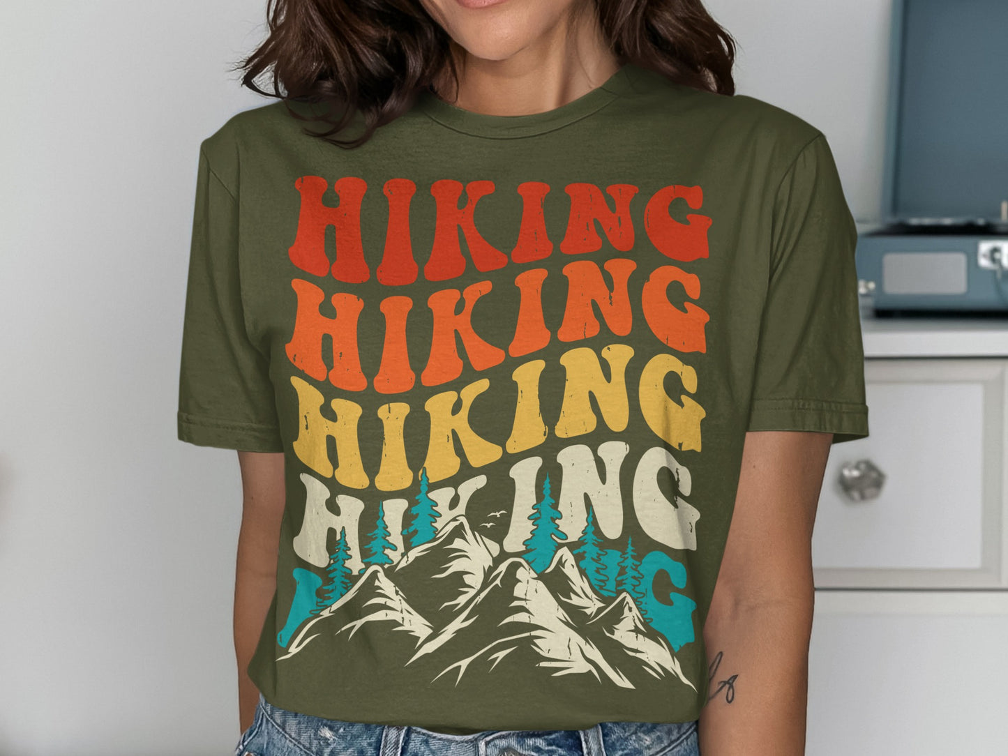 Green t-shirt with "HIKING" in colorful retro lettering over mountains and trees.