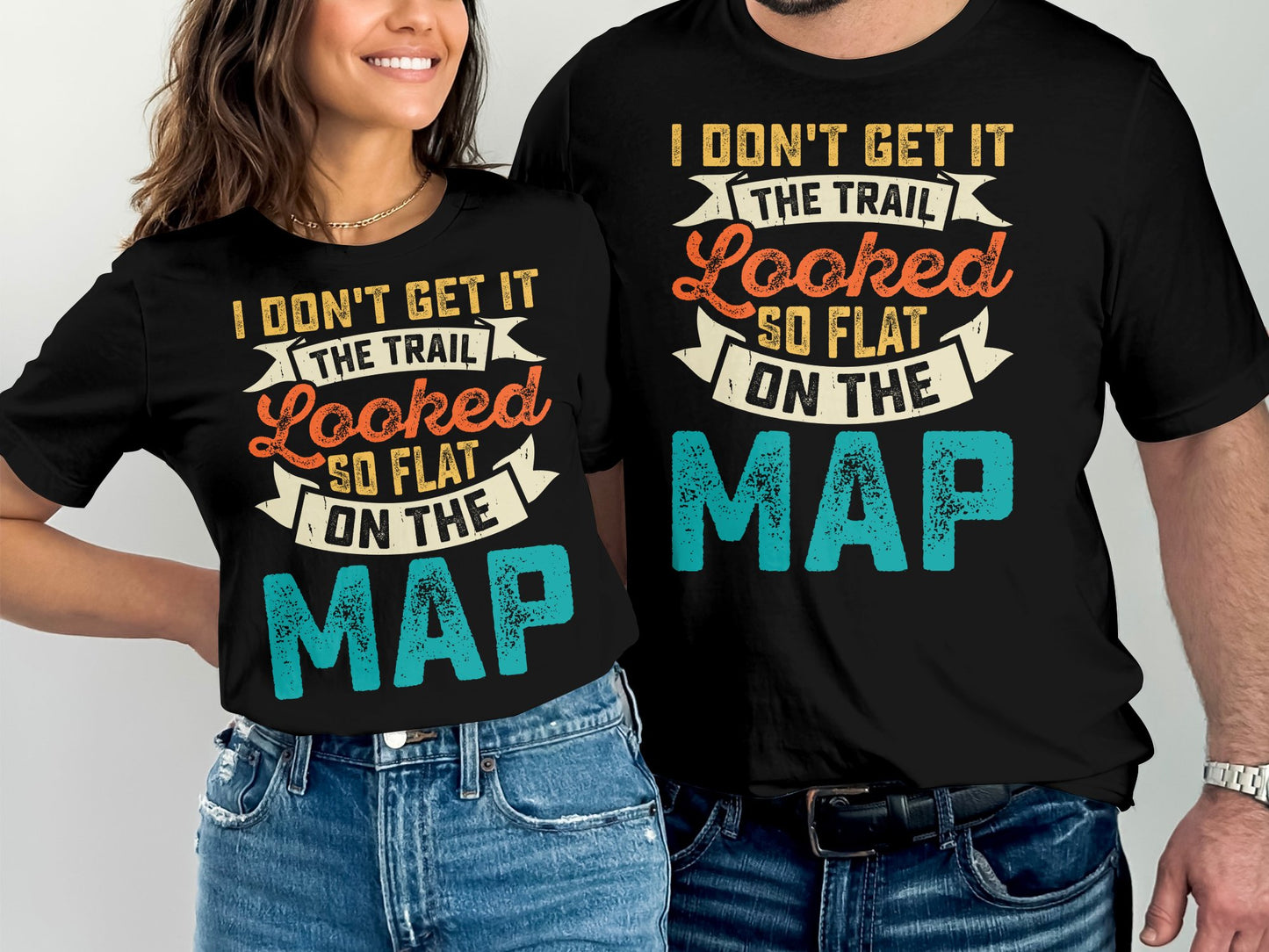 Couple wearing black t-shirts with "I Don't Get It The Trail Looked So Flat On The Map" text.