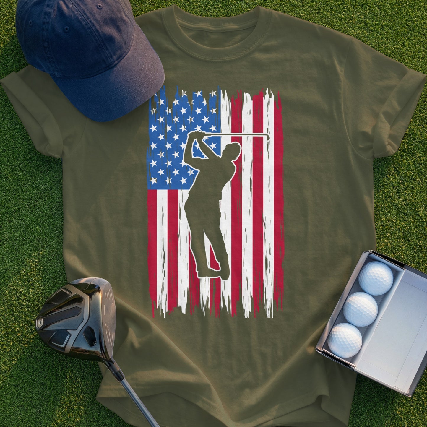 Golfer silhouette over distressed American flag on olive green t-shirt.