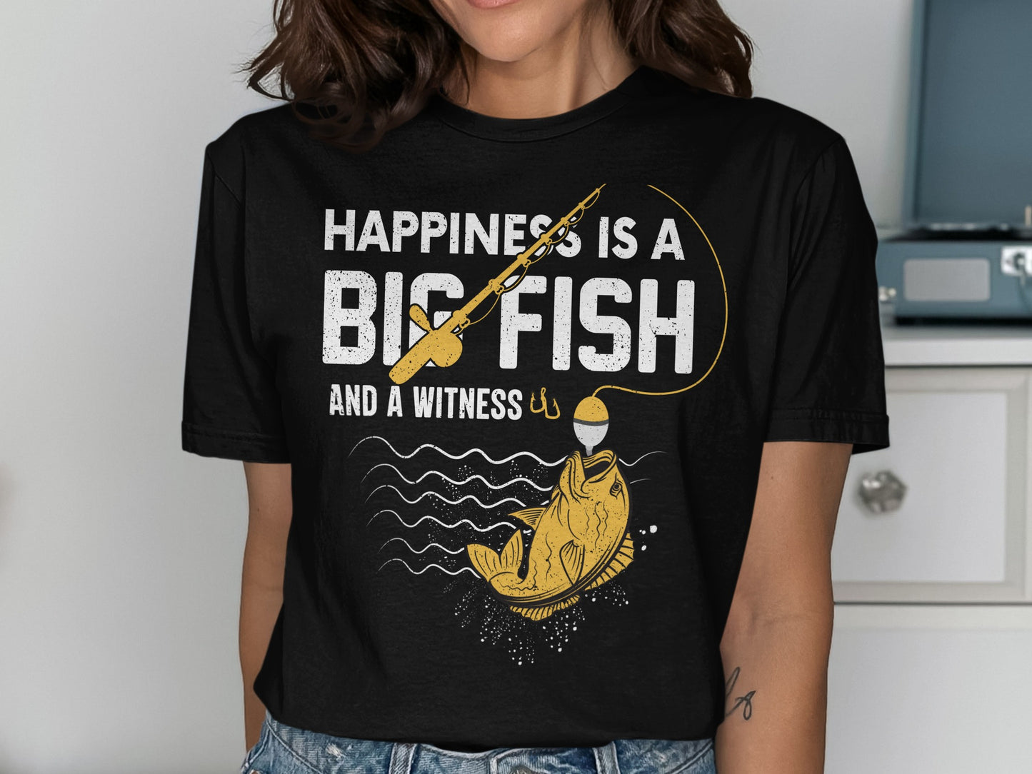 White t-shirt with text "HAPPINESS IS A BIG FISH AND A WITNESS" and fishing graphic.