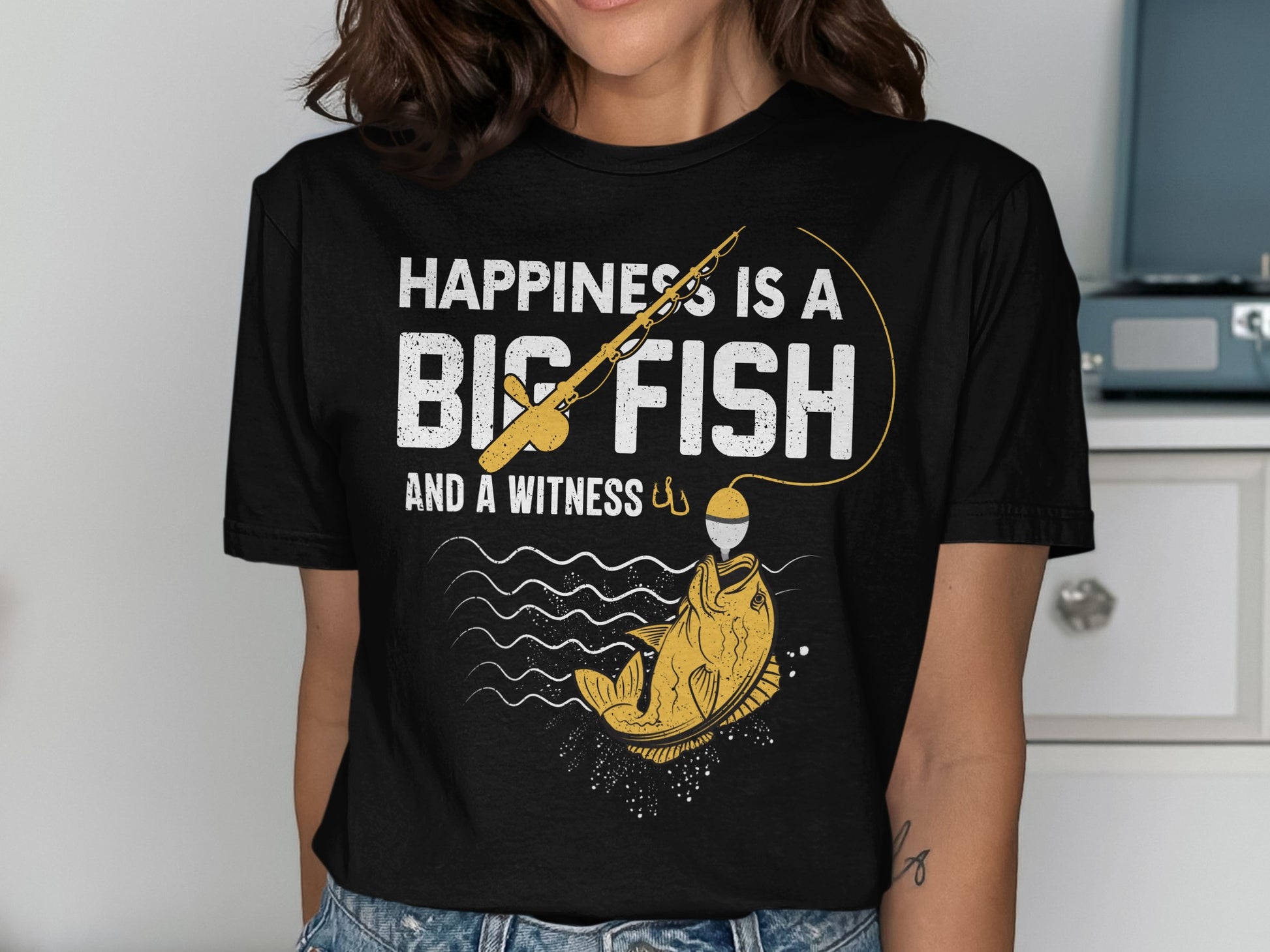 White t-shirt with text "HAPPINESS IS A BIG FISH AND A WITNESS" and fishing graphic.