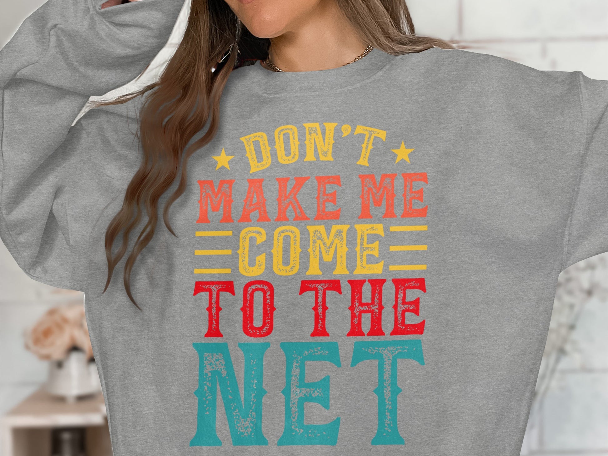 Gray sweatshirt with "Don't Make Me Come To The Net" text in colorful block letters.