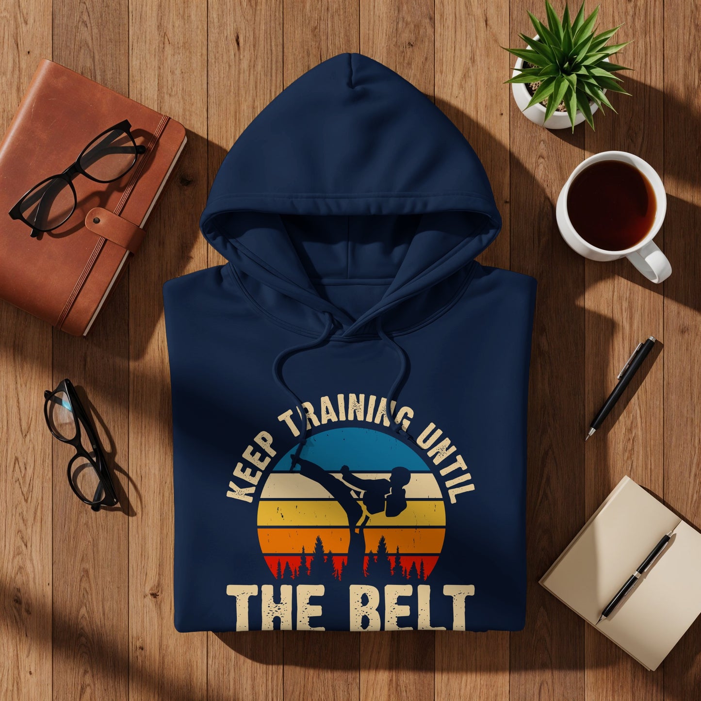 Navy hoodie with "Keep training until the belt" text and martial arts graphic.