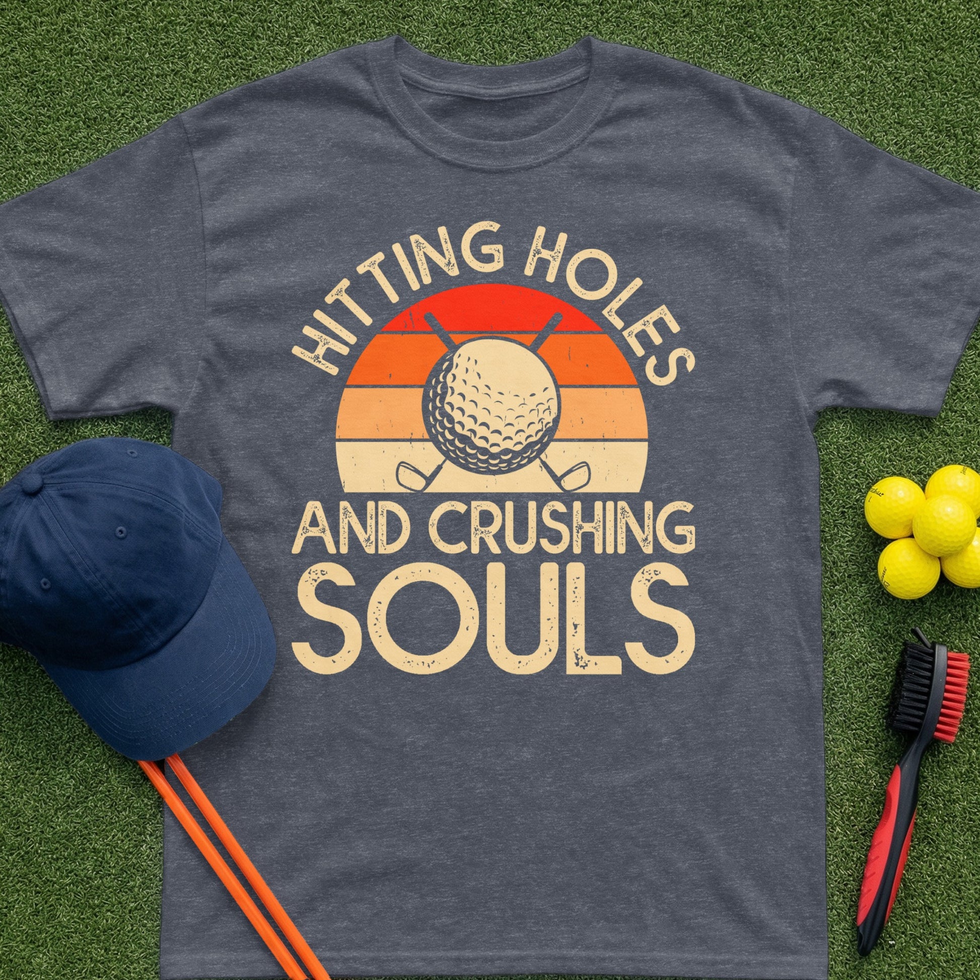 T-shirt with "Hitting Holes And Crushing Souls" text and golf ball sunset graphic.