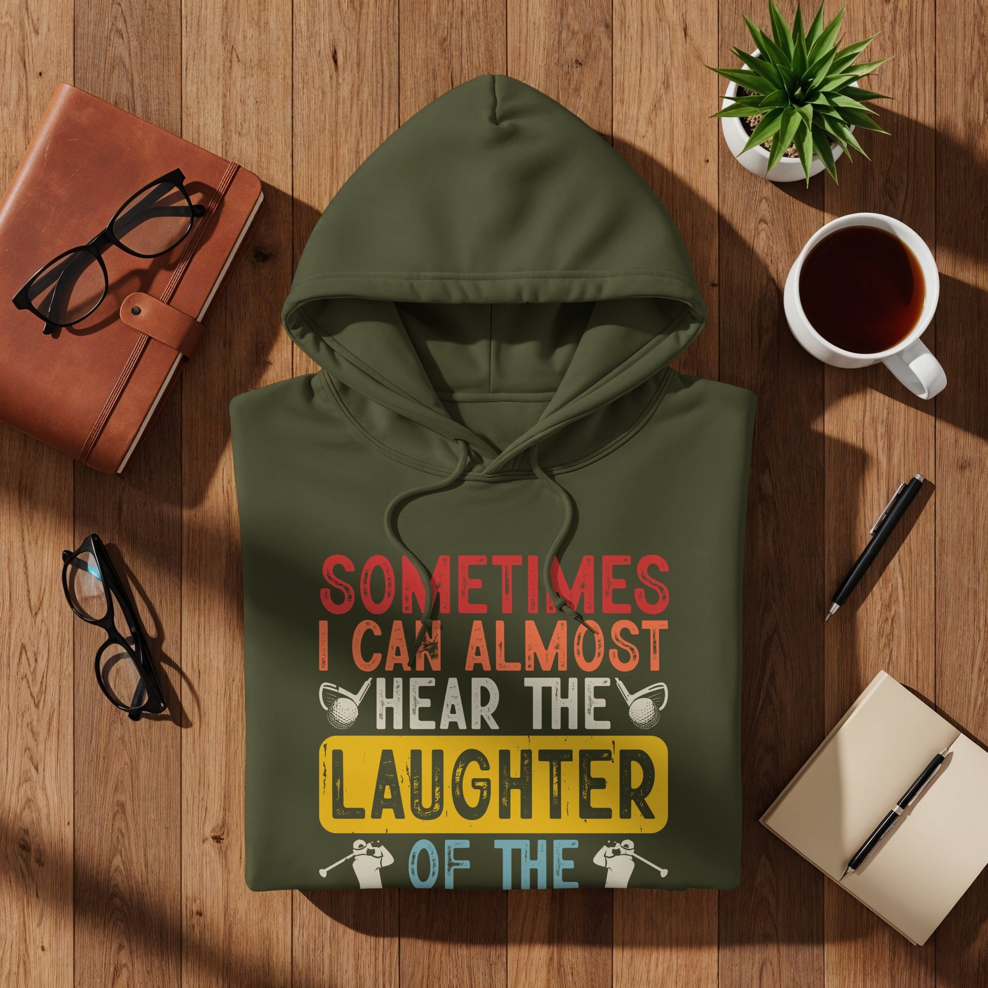 Olive green hoodie with "Sometimes I Can Almost Hear The Laughter Of The" text.