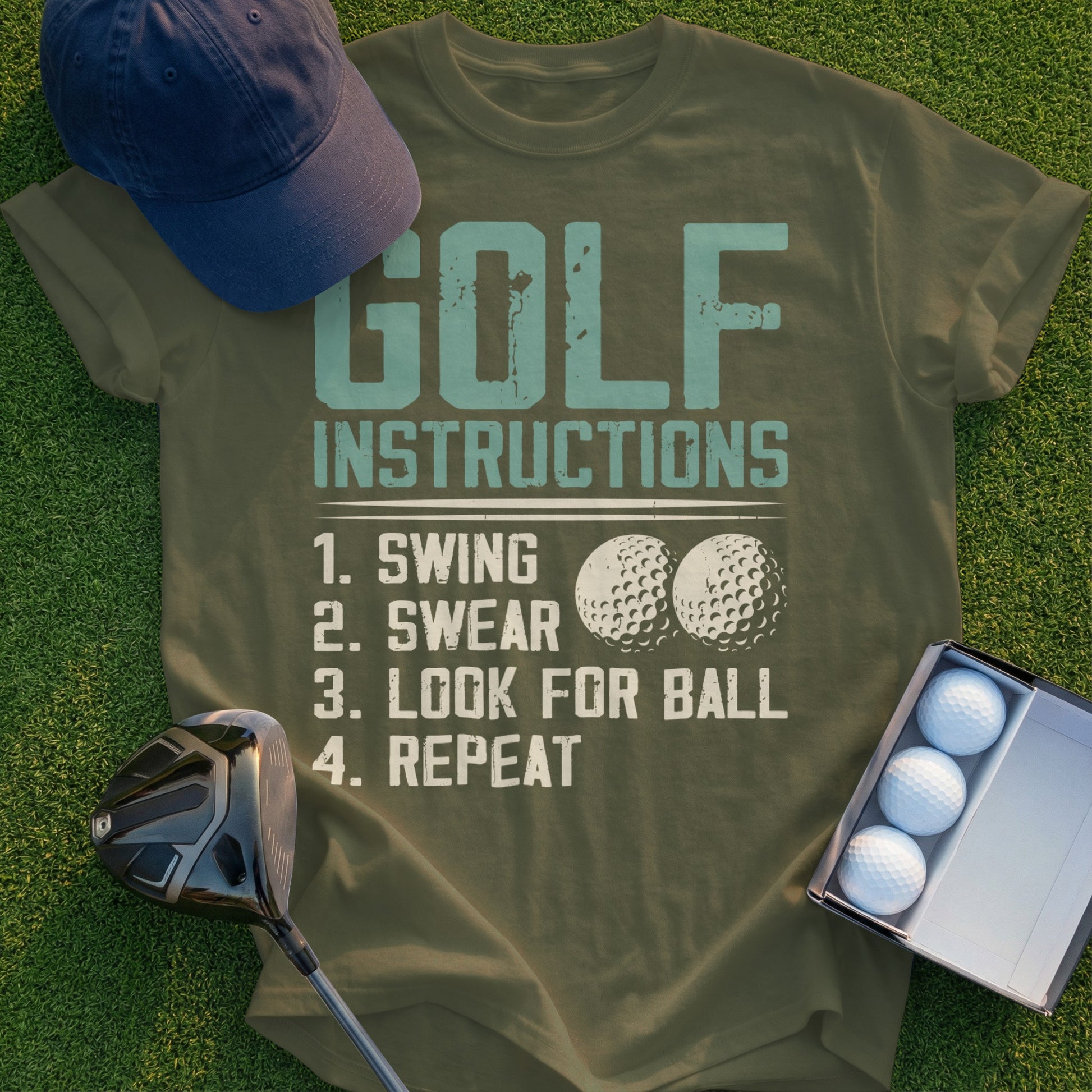 Olive green t-shirt with "GOLF INSTRUCTIONS: 1. SWING, 2. SWEAR, 3. LOOK FOR BALL, 4. REPEAT" and golf balls.
