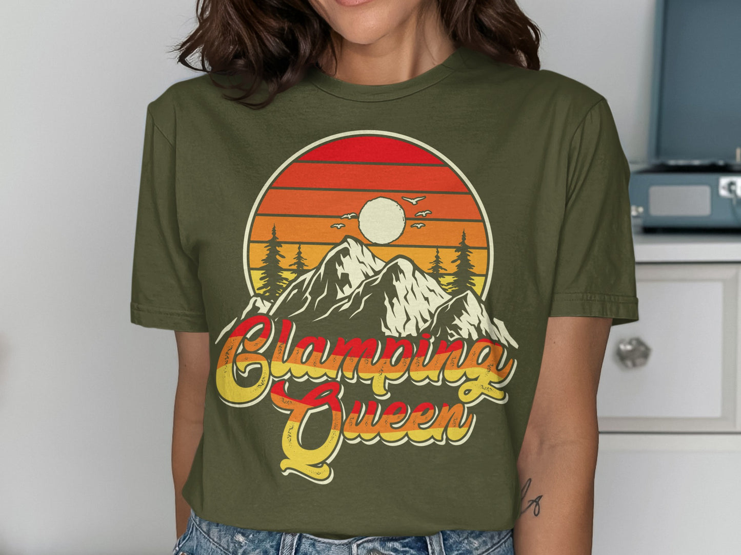 Olive green t-shirt with "Glamping Queen" text and mountain sunset graphic.