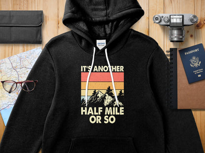 Black hoodie with "IT'S ANOTHER HALF MILE OR SO" mountain graphic.
