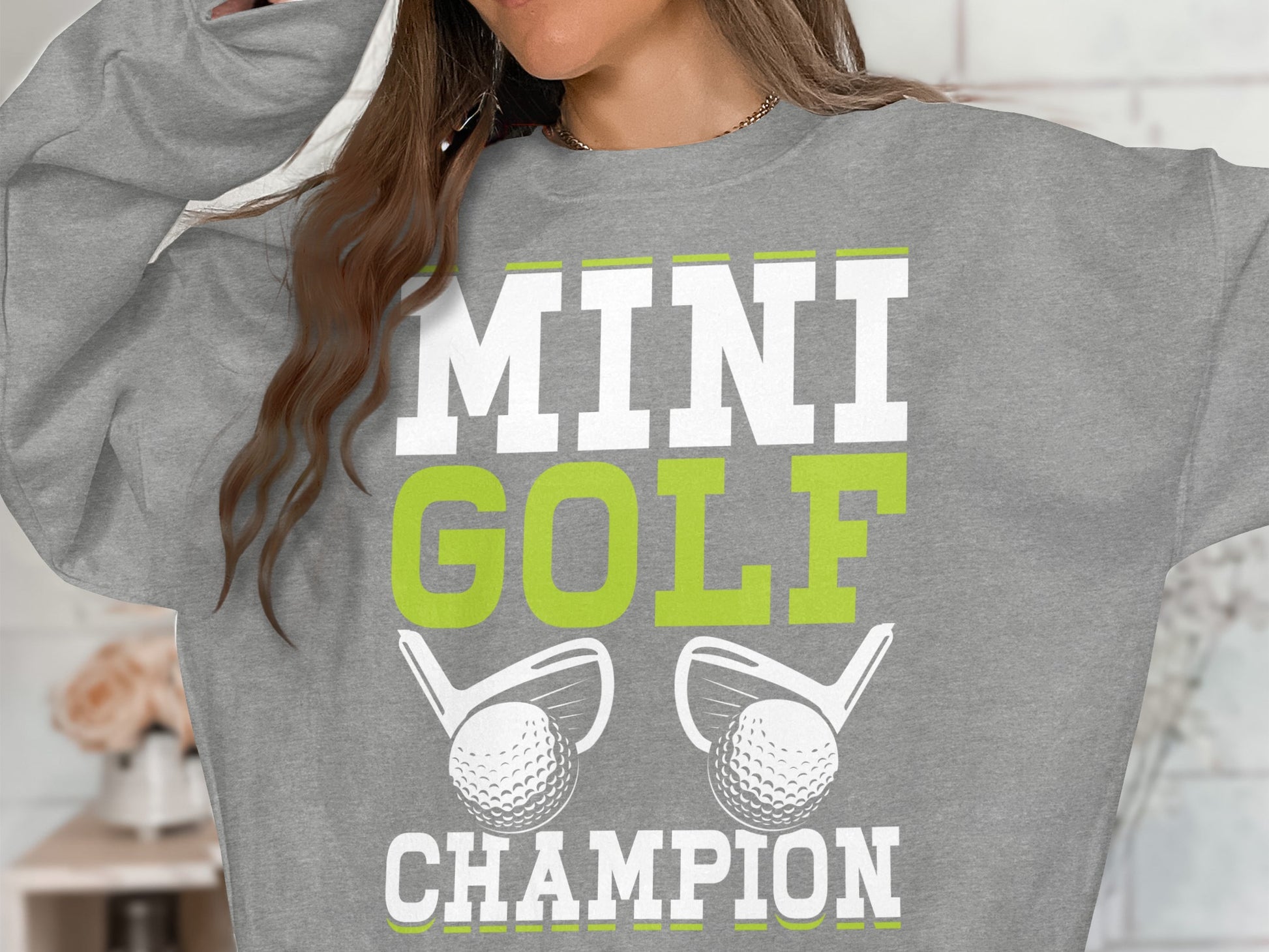 Grey sweatshirt with "MINI GOLF CHAMPION" and golf clubs and balls.