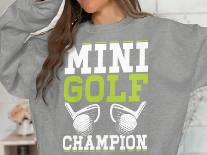 Grey sweatshirt with "MINI GOLF CHAMPION" and golf clubs and balls.