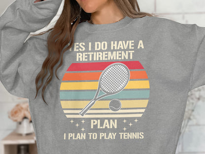 Gray sweatshirt with retro tennis graphic and "YES I DO HAVE A RETIREMENT PLAN I PLAN TO PLAY TENNIS" text.