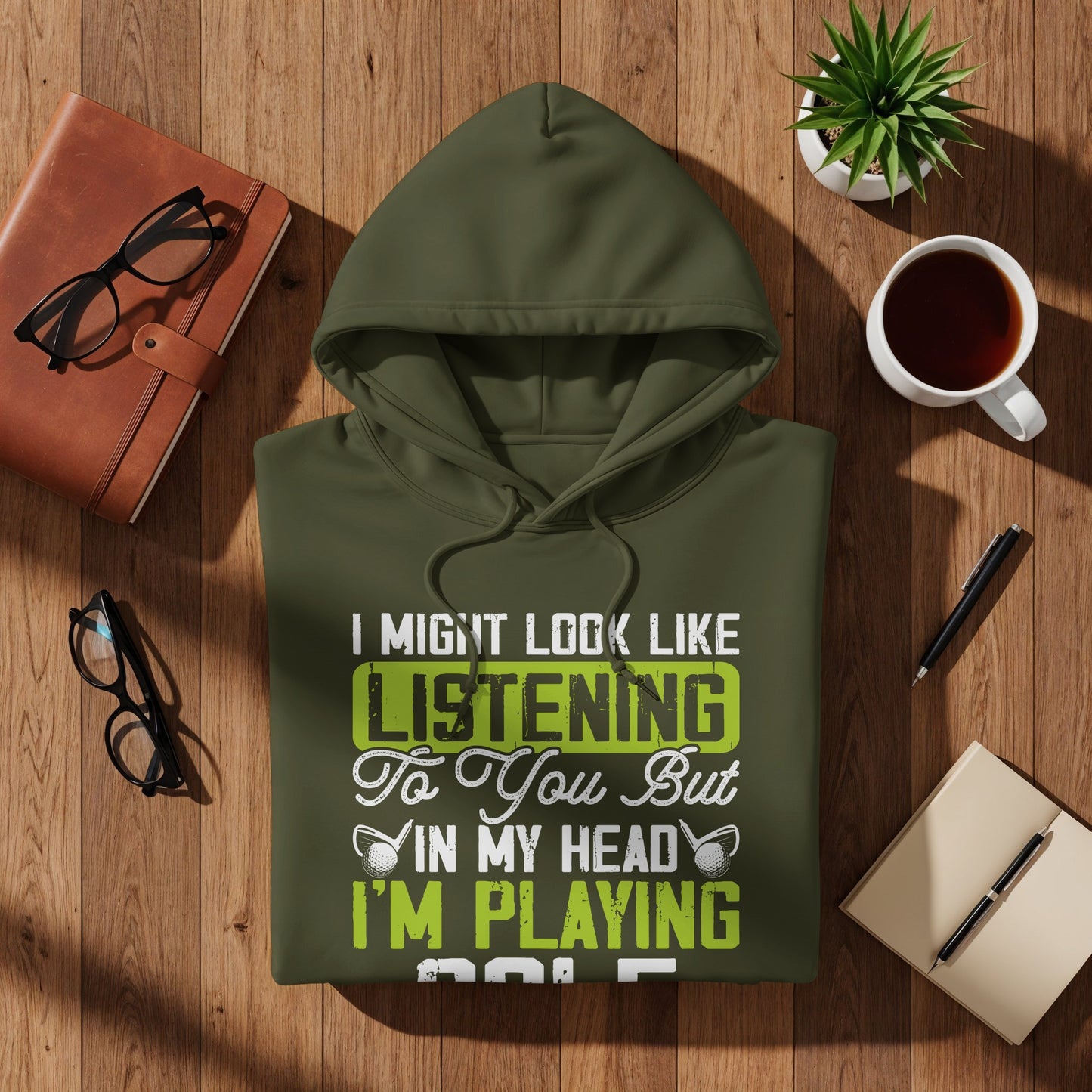 Olive green hoodie with text "I MIGHT LOOK LIKE LISTENING To You But IN MY HEAD I'M PLAYING GOLF".