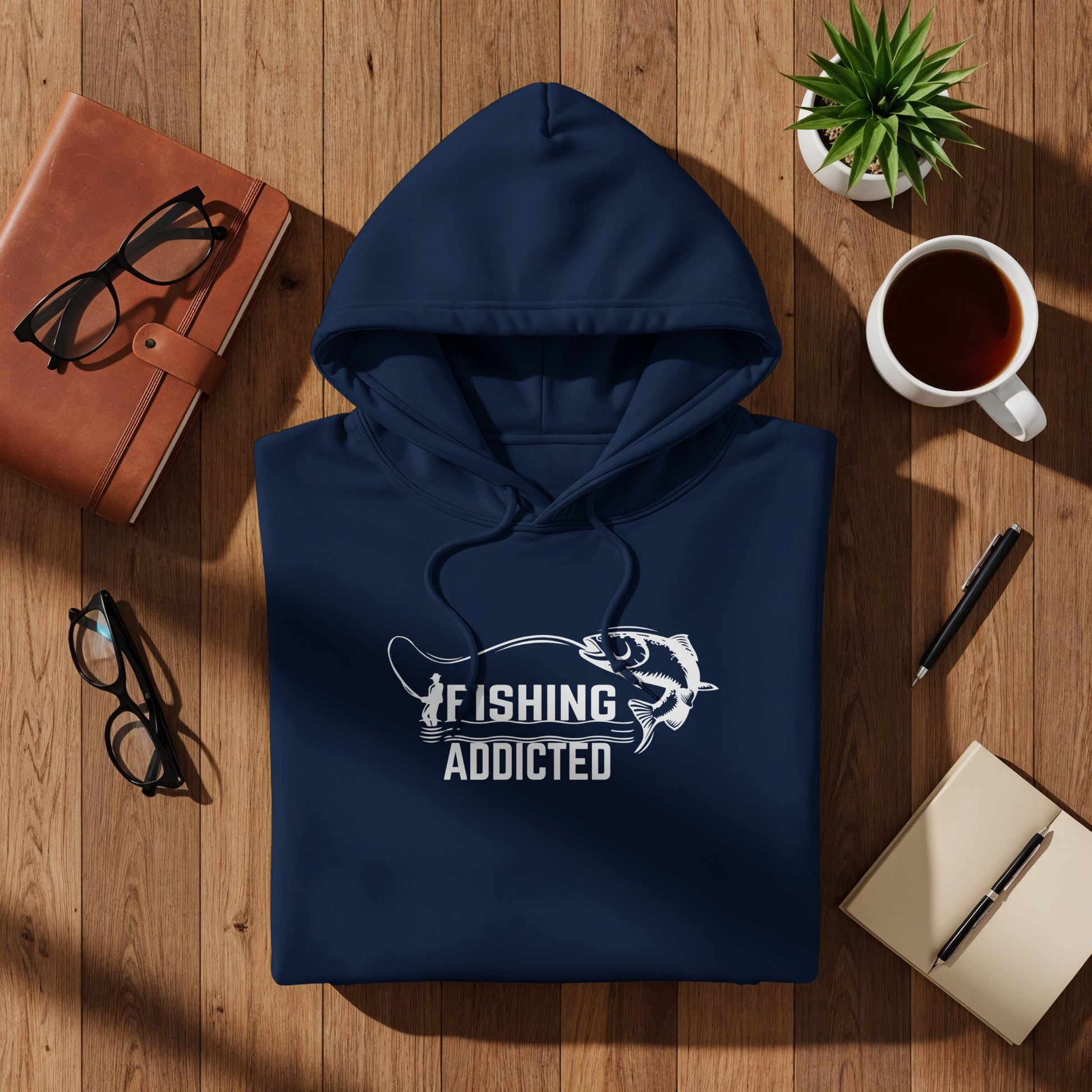 Navy hooded sweatshirt with "FISHING ADDICTED" graphic on wooden background.