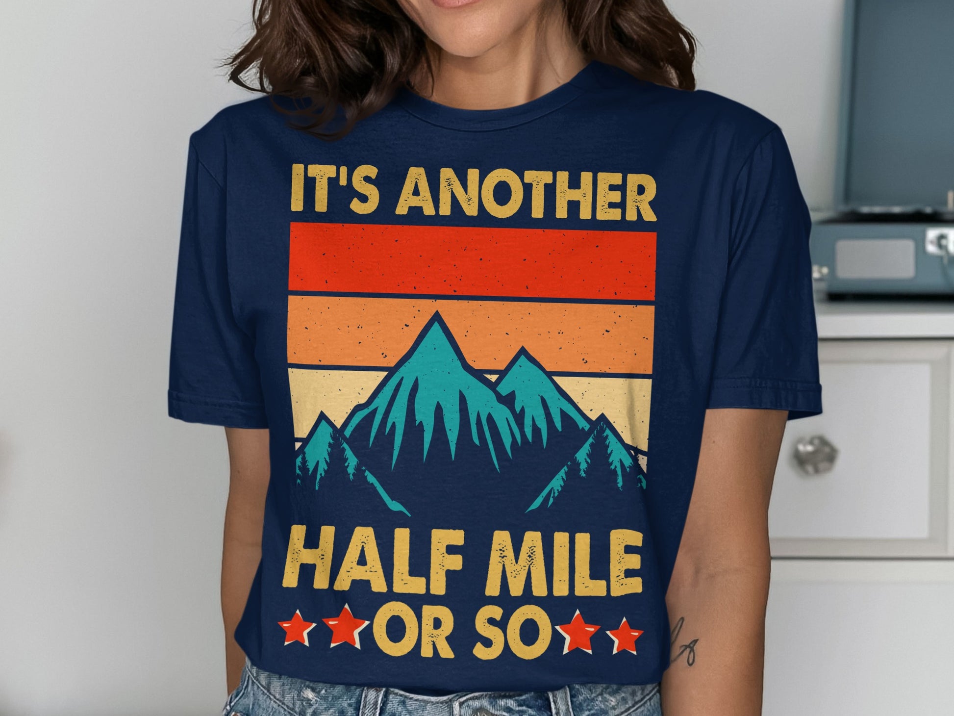 T-shirt with retro mountain graphic and text "IT'S ANOTHER HALF MILE OR SO".