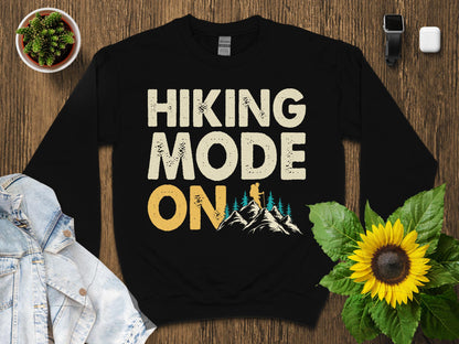 Black crewneck sweatshirt with "HIKING MODE ON" text and mountain graphic.