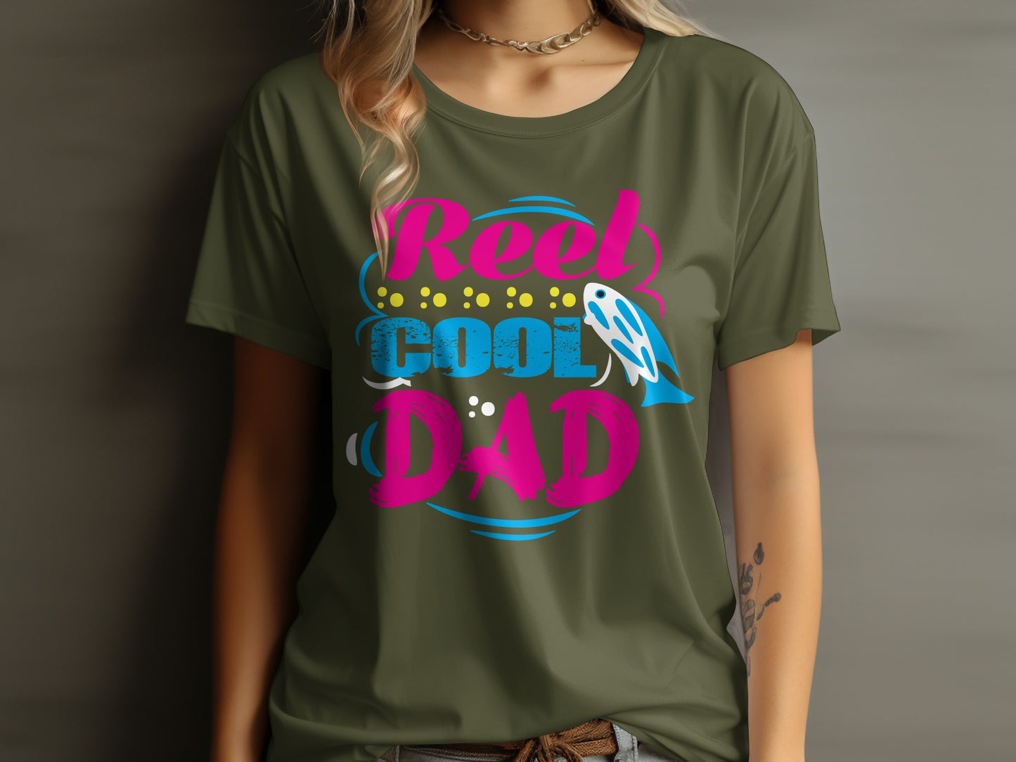 Olive green t-shirt with pink and blue "Reel Cool Dad" text and fish graphic.