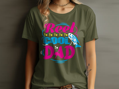 Olive green t-shirt with pink and blue "Reel Cool Dad" text and fish graphic.