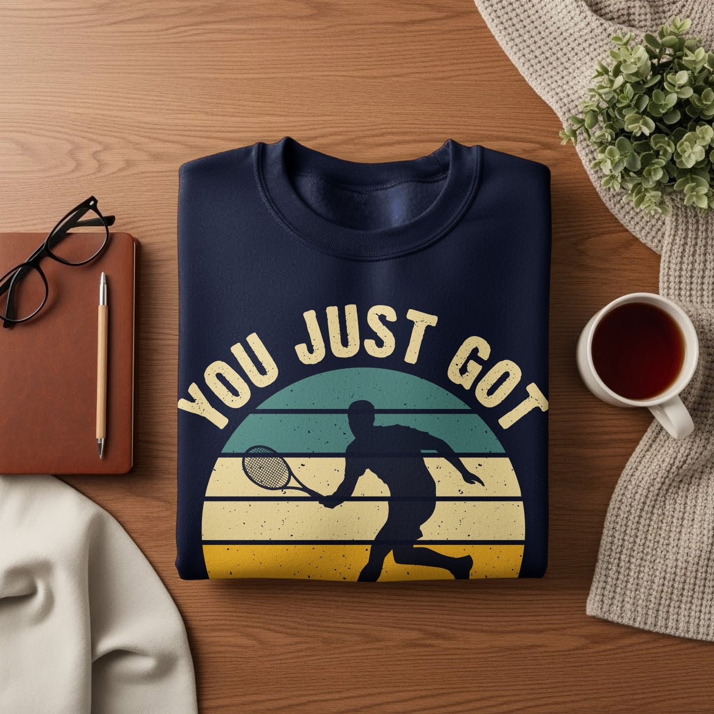 Navy sweatshirt with "YOU JUST GOT" text and tennis player silhouette against a sunset graphic.